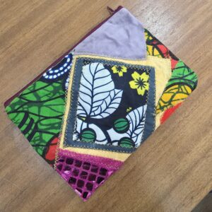 ACAP Made patchwork zipper pouch, front: black and white leaf wax-print panel with yellow flowers, lilac velvet corner, pink sequin net and green, red and orange wax prints, with a burgundy zip
